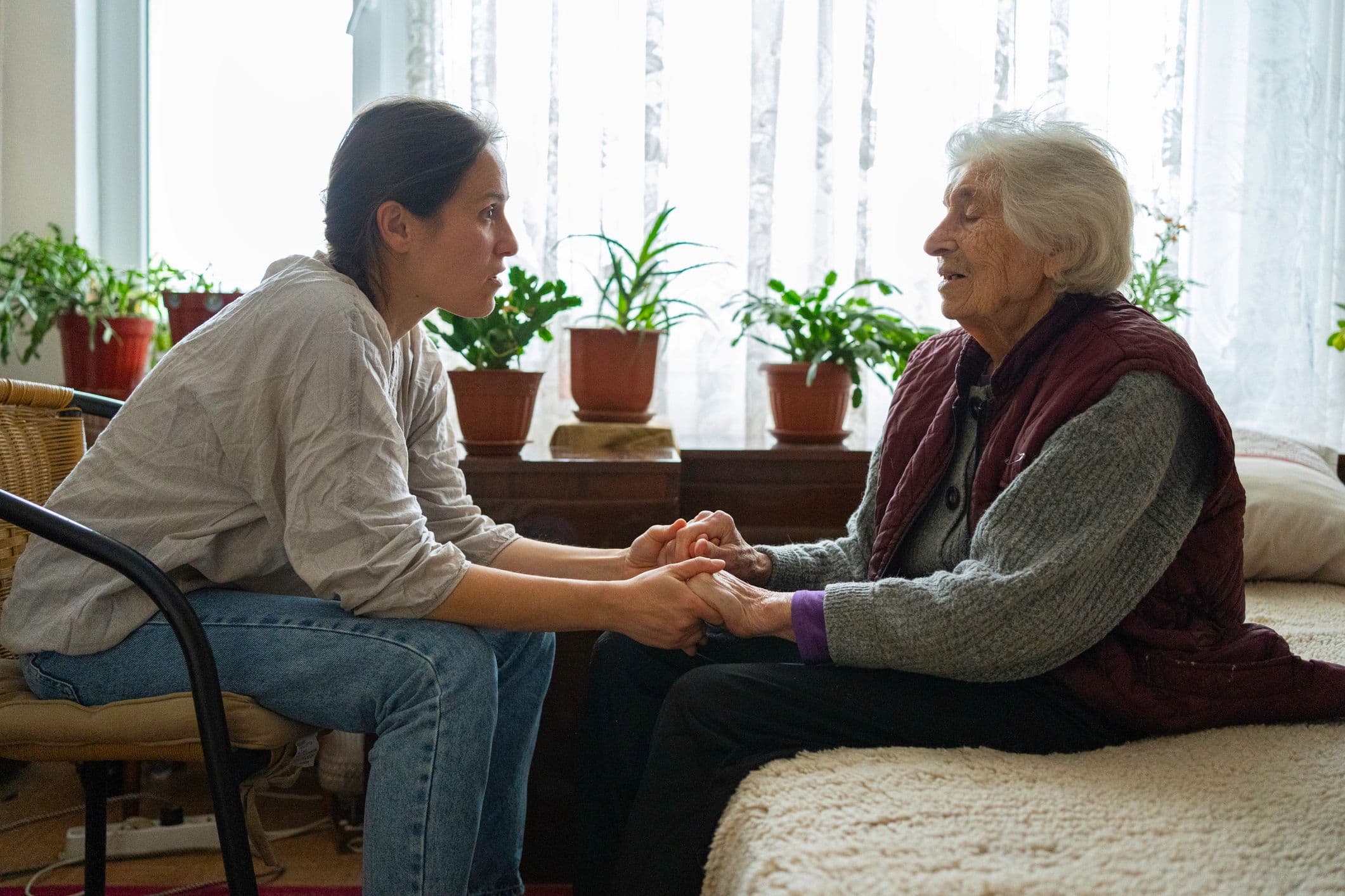 Caregiver holding an older woman's hands and listening