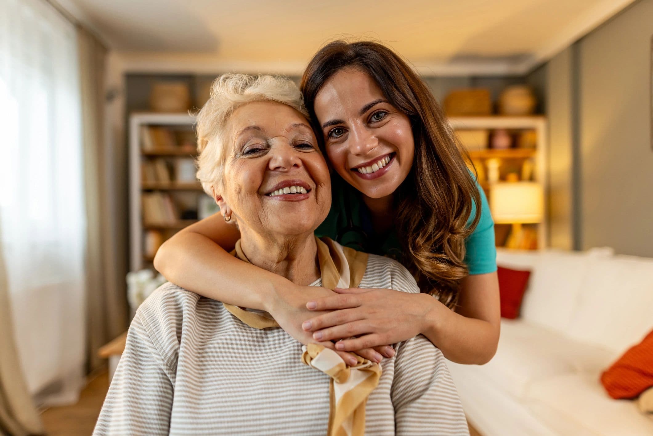 Caregiver embracing a smiling older woman at home