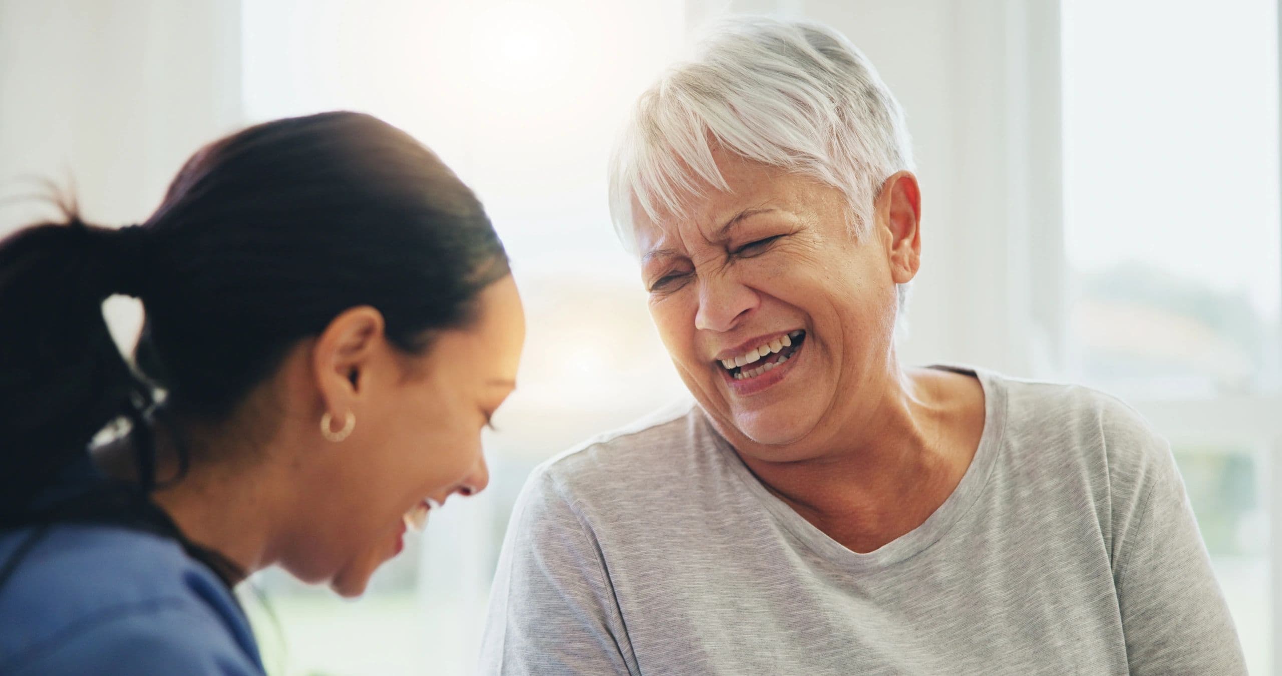Caregiver and older woman laughing together